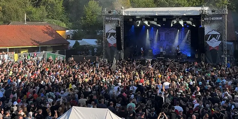 Eine große Menschenmenge versammelt sich vor einer Bühne bei einem Open-Air-Konzert.