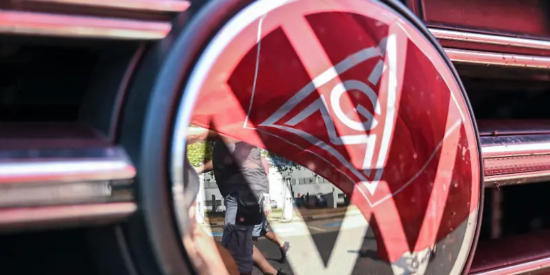 Eine Fahne der IG Metall spiegelt sich in einem VW Logo