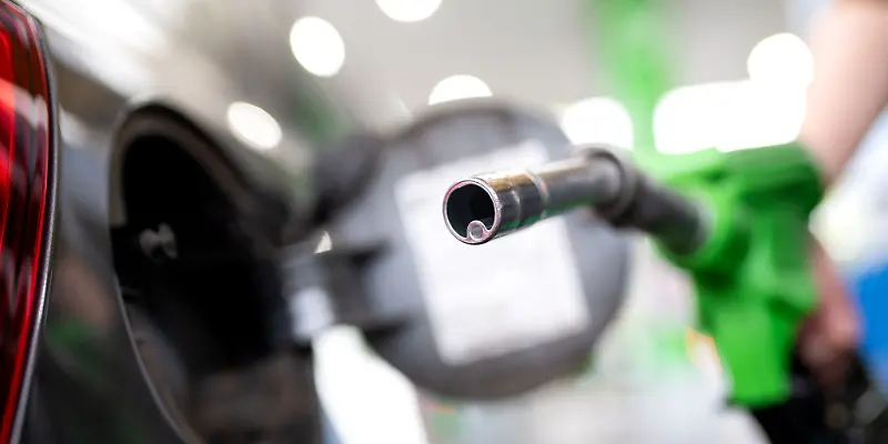 Eine Hand führt eine Zapfpistole an einer Tankstelle zur Tanköffnung